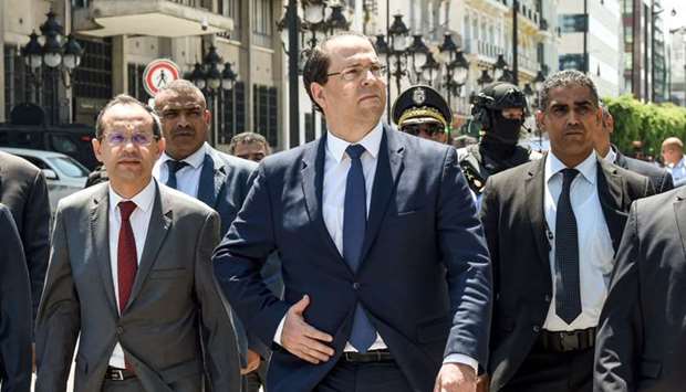 Tunisian Prime Minister Youssef Chahed (C) walks with Interior Minister Hichem Fourati (L) outside the Interior Ministry headquarters near the scene of a suicide attack on police and national guardsmen in the capital Tunis' main avenue Habib Bourguiba