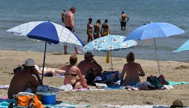 People on the beach protect themselves from the sun under umbrellas during a heat wave in Palavas-les-Flots, southern France