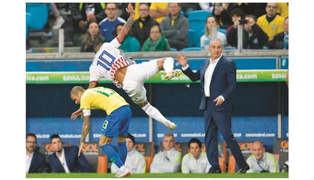 Brazilu2019s Dani Alves (left) and Paraguayu2019s Derlis Gonzalez vie for the ball as Brazilu2019s coach Tite (right) looks on during the Copa America quarter-final match in Porto Alegre, Brazil. (AFP)
