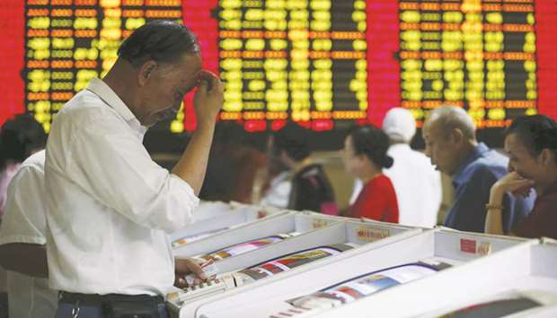 Investors look at computer screens showing stock information at a brokerage house in Shanghai. The Composite closed down 0.6% to 2,978.88 points yesterday.