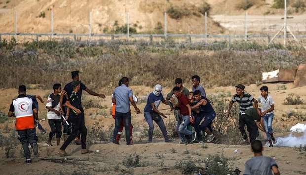 Palestinian protesters carry way an injured youth during clashes with Israeli forces near the fence along the border, near Bureij in the central Gaza Strip, yesterday.