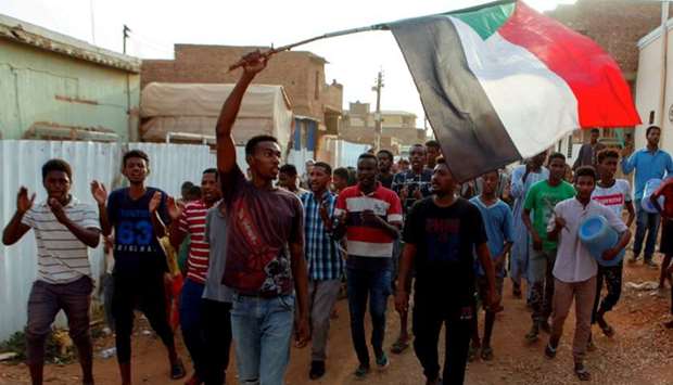 Sudanese protesters chant slogans and wave their national flag as they demonstrate against the ruling military council, Thursday in Khartoum