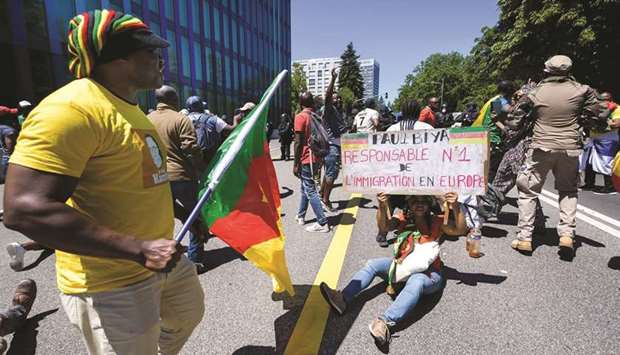 A woman holds a banner reading u2018Paul Biya first responsible for immigration in Europeu2019 during a protest yesterday in Geneva against visiting Cameroon President Paul Biya.