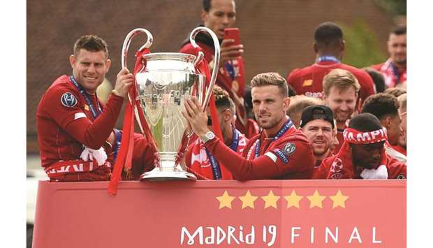 Liverpoolu2019s English midfielder James Milner (left) and midfielder Jordan Henderson hold the European Champions League trophy during an open-top bus parade around Liverpool, north-west England after winning the UEFA Champions League final against Tottenham. (AFP)