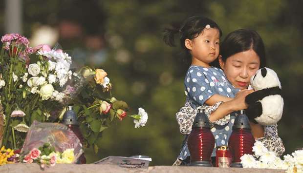 A woman and her child are seen at a makeshift shrine near the Margaret bridge, by the Danube, in Budapest.
