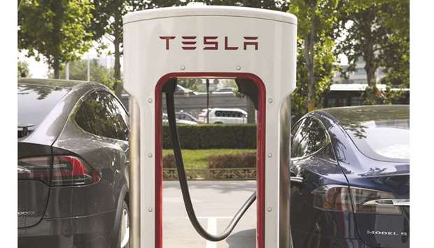 The Tesla logo is displayed on an electric vehicle charging station outside one of the companyu2019s showrooms in Beijing. Shunde New Energy Vehicle Town is one of at least 20 electric-centric versions of Detroit under construction as China goes all-in on a technology projected to sell in record numbers this year.
