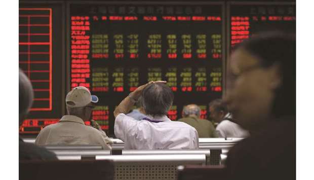 Investors look at screens showing stock market movements at a securities company in Beijing. The Composite closed down 0.3% to 2,890.08 points yesterday.
