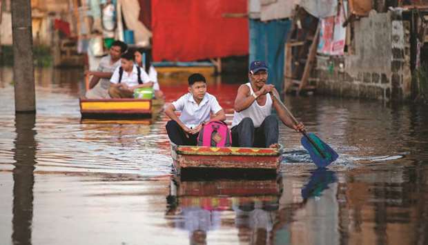 Elementary students, living on flooded Artex Compound, ride on a makeshift boat to attend the first day of school in Panghulo 1 Elementary School in Malabon, north of Manila, yesterday.