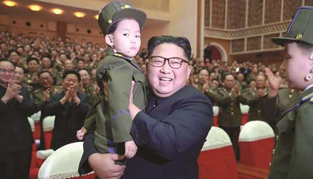 North Korean leader Kim Jong-un holding a child while visiting the performance given by amateur art groups of the wives of officers of units of the Korean Peopleu2019s Army (KPA) at an undisclosed location.