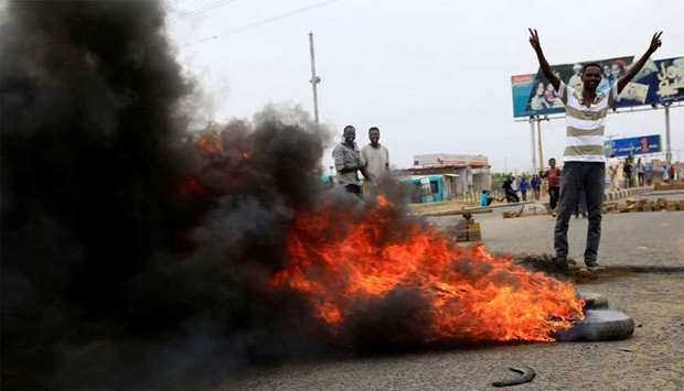A Sudanese protester gestures near burning tyres used to erect a barricade on a street, demanding that the country's Transitional Military Council handover power to civilians, in Khartoum