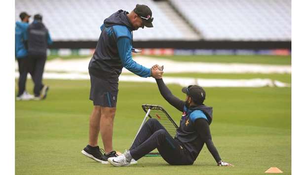 Pakistan all-rounder Mohamed Hafeez (right) is helped to his feet by head coach Mickey Arthur during a training session in Nottingham, England, on Sunday. (AFP)