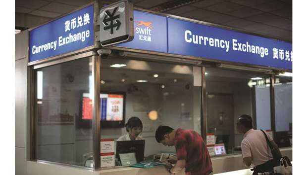 A man changes foreign currency into Chinese yuan at a currency exchange office in Hongqiao airport in Shanghai. The yuan inched lower yesterday as broad weakness in the greenback prompted corporate buying interest.