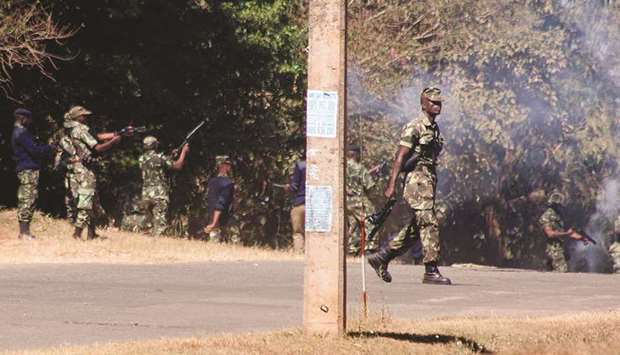 Armed Malawian policemen walk through teargas as they disperse supporters of the Malawi Congress Party (MCP) in Lilongwe yesterday.