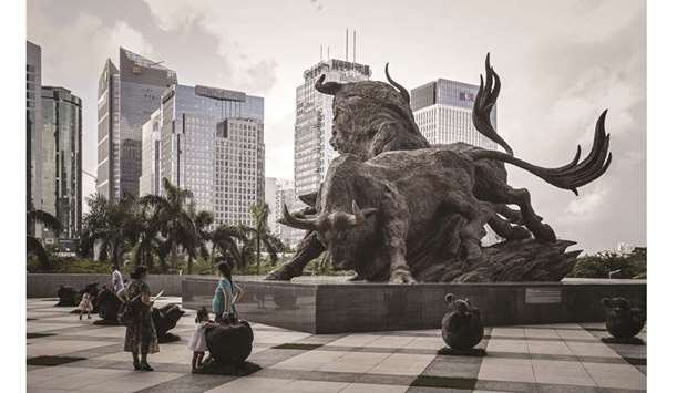 People stand in front of a sculpture of bulls at the entrance to the Shenzhen Stock Exchange building in China. The Shanghai and Shenzhen stock exchanges sent out a total of at least 1,149 queries to listed companies in the first five months of this year, up 23% from the year-earlier period and 62% more than the 2017 tally, according to data compiled by Bloomberg.