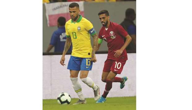 Qatar captain Hassan al-Haydos (right) and his Brazilian counterpart Dani Alves vie for the ball during the International Friendly match in Brasilia on Wednesday.
