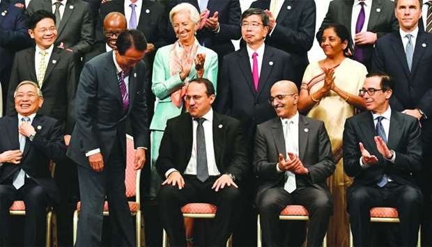 Japanese Finance Minister Taro Aso (front, second left) is welcomed by IMF managing Director Christine Lagarde (top, third left), US Treasury Secretary Steven Mnuchin (front, right), and other delegation members while arriving at a family photo session of the G20 finance ministers and central bank governors meeting in Fukuoka, Japan