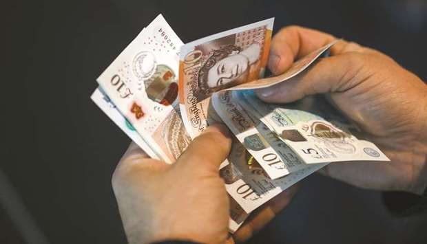 A man holds a selection of pound sterling banknotes in an arranged photograph in London. The pound may slide to a two-year low if a hardline euro-sceptic takes over as UK prime minister, according to a Bloomberg survey of analysts.