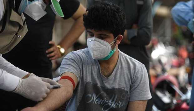A health official wearing protective gear takes a blood sample from a man at a drive-through screening and testing facility for the coronavirus, alongside a street in Islamabad yesterday.