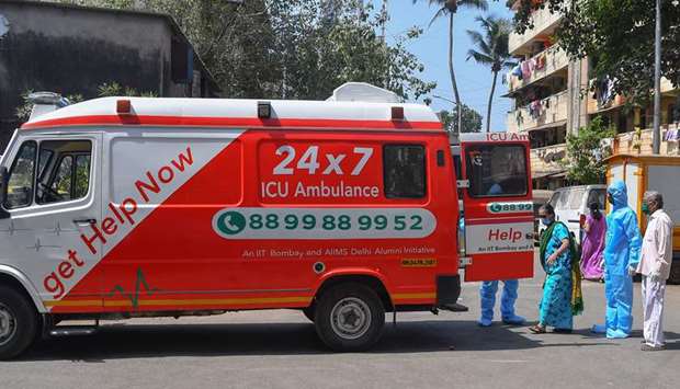 HelpNow ambulance staff wearing protective gear escort a patient aboard an ambulance before driving to a government hospital in Mumbai.