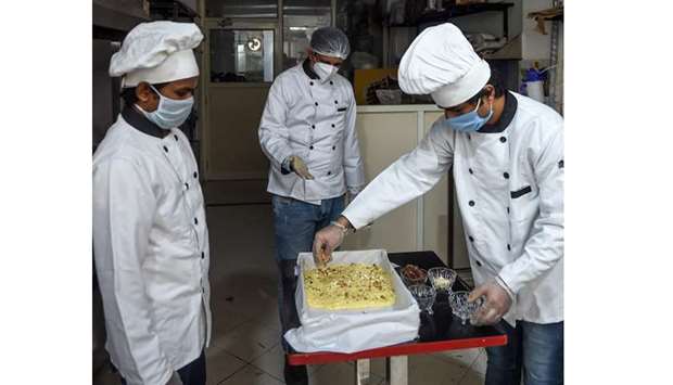 u2018Cakelicious and the Cake Studiou2019 owner Gunjan Parmar (centre) watches his employees preparing a baked tea-time cake made of ingredients that are said to boost the immunity system in the shopu2019s kitchen in Ahmedabad yesterday.