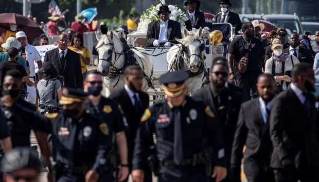 A row of police officers walk ahead of the horse-drawn carriage coffin of George Floyd, whose death in Minneapolis police custody has sparked nationwide protests against racial inequality, before his burial at the Houston Memorial Gardens cemetery in Pearland, Texas, US