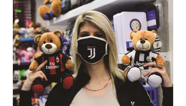 A woman wearing a protective face mask poses with AC Milan and Juventus teddy bears in a shop on the eve of the Coppa Italia semi-final in Turin, Italy. (Reuters)