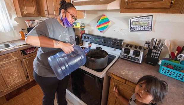 Amanda Larson who has no running water at her home, carries water for her son Gary Jr to have a bath in the Covid-19 virus affected Navajo Nation town of Thoreau in New Mexico on May 22.