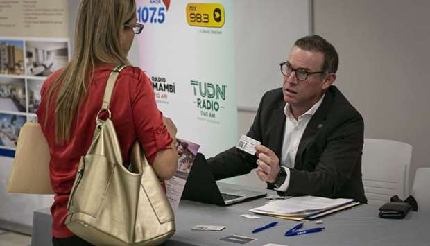 A representative hands a business card to a job seeker during a job fair for in Miami, Florida. Initial jobless claims for regular state programmes totaled 1.54mn in the week ended June 6, down from 1.9mn in the prior week, Labour Department figures showed yesterday.