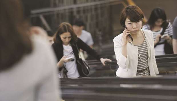 A woman talks on a mobile phone as she rides on an escalator in Tokyo. Helped by a worker shortage, female labour participation hit a decade-high of more than 70% in Japan under Abeu2019s campaign, often dubbed u201cWomenomicsu201d. The catch: many women lack the job security of male workers, with more than half holding vulnerable part-time, contract or temporary jobs.