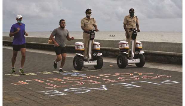 Police officers patrol on Segways as men run along the promenade at Marine Drive, after authorities eased lockdown restrictions that were imposed to slow the spread of the coronavirus, in Mumbai, yesterday.