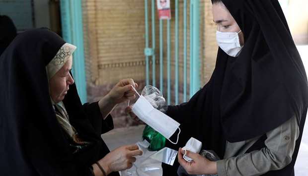 An Iranian woman gives a protective face mask to a worshipper to attend the Friday prayers at the  Qarchak Jamee Mosque, following the outbreak of the coronavirus disease (Covid-19), in the Tehran province, yesterday.