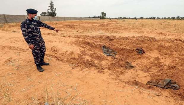A member of security forces affiliated with the Libyan Government of National Accord (GNA)'s Interior Ministry stands at the reported site of a mass grave in the town of Tarhuna