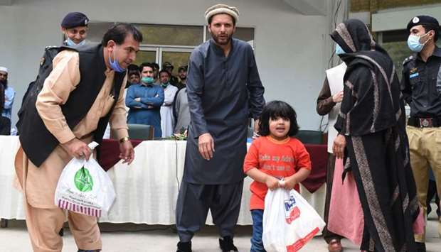 Pakistan's cricketer Shahid Afridi (C) distributes dry food rations to family members of policemen, who died in service, during a government-imposed nationwide lockdown as a preventive measure against the Covid-19  in Quetta on May 4.