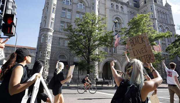 Demonstrators react as they march past the Trump International Hotel in Washington during a protest against the death of George Floyd, near the White House in Washington.
