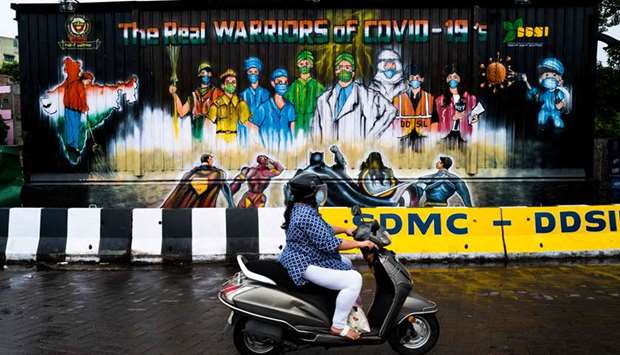 A woman rides past a mural painted on a garbage dump after the government eased a nationwide lockdown imposed as a preventive measure against the Covid-19, in New Delhi yesterday.