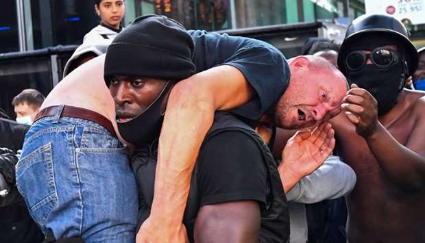 A protester carries an injured counter-protester to safety, near the Waterloo station during a Black Lives Matter protest following the death of George Floyd in Minneapolis police custody, in London