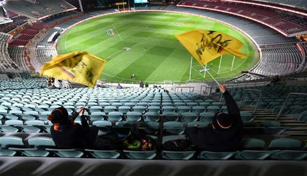 Fans wave flags before an Australian Football League (AFL) match between the Port Adelaide Power and Adelaide Crows amidst the easing of the coronavirus disease restrictions at Adelaide Oval in Adelaide, Australia