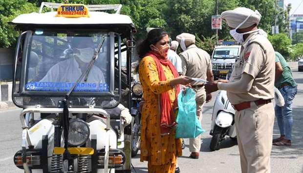 A policeman checks the travel pass of a commuter after strict lockdown norms for weekends and public holidays were imposed, in Amritsar, Punjab yesterday.