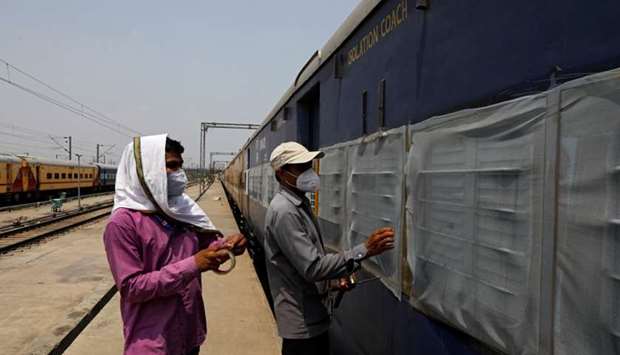 Workers fix mosquito nets on a parked passenger train that will be equipped for the care of coronavirus disease patients amidst the spread of the disease, at a railway yard in New Delhi