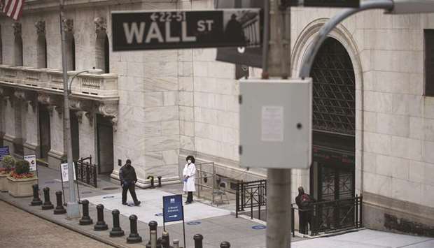 A healthcare worker stands in front of an entrance to the New York Stock Exchange. Right on cue, fresh waves of selling are hitting Wall Street trading desks as signs emerge of a second virus outbreak.