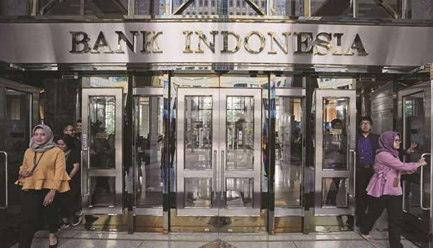 People exit the Bank Indonesia headquarters in Jakarta (file). The Bank Indonesia will cut its policy rate for the third time this year, according to a Bloomberg survey of economists.
