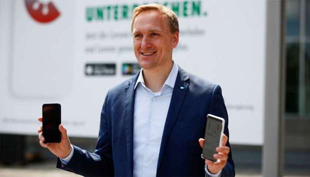 Member of the Executive Board of SAP Juergen Mueller (Chief Technology Officer) holds mobile phones as he attends the presentation of the new contact-tracing smartphone app that will use Bluetooth short-range radio and technology standards from Apple and Google to alert people of the risk of infection with the coronavirus disease (COVID-19), in Berlin, Germany