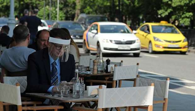 A man wearing a protective face shield sits in a cafe as restaurants and cafes reopen summer terraces following the easing of measures against the spread of the coronavirus disease, in Moscow, Russia