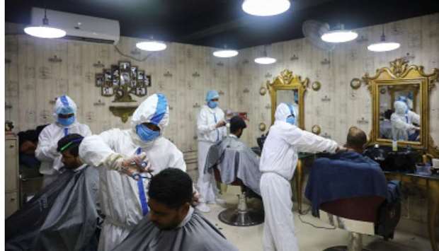Barbers wearing protective suits and face masks provide hair cut service to the customers inside a salon amid the coronavirus disease (Covid-19) outbreak, in Dhaka yesterday.