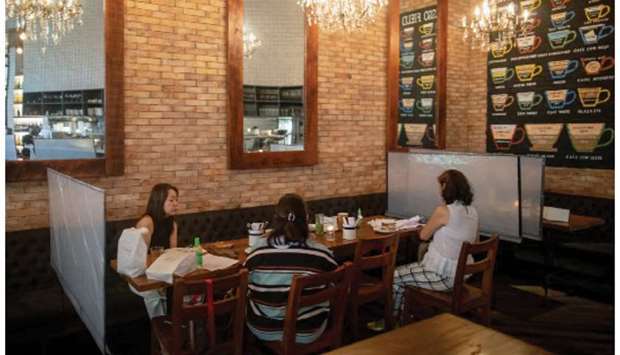 Customers eat at a restaurant where plastic barriers are installed in-between tables as the government allows dining-in following months of restrictions due to the coronavirus disease (Covid-19) outbreak, in Mandaluyong City, Metro Manila, yesterday.