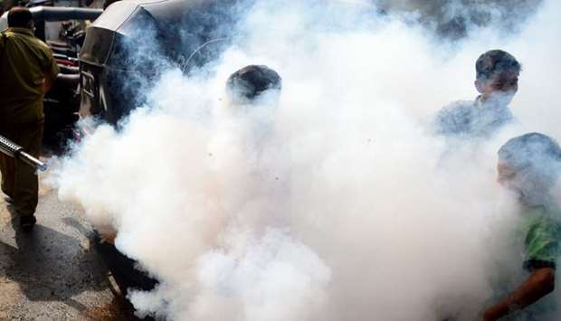 Children are covered in smoke as a civic authority worker fumigates a slum area to kill disease-carrying mosquitoes in Mumbai ahead of the onset of monsoon season.