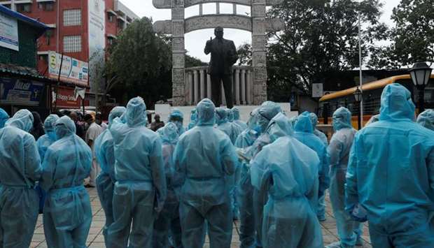Healthcare workers stand in front of a statue of Babasaheb Ambedkar, founder of the Indian Constitution, before the start of a check-up camp for the coronavirus disease in Mumbai.