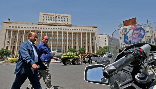 Men walk outside the Central Bank of Syria headquarters in the Sabaa Bahrat Square of the capital Damascus yesterday. The United States yesterday imposed its toughest sanctions ever targeting Syrian President Bashar al-Assad to choke off revenue for his government in a bid to force it back to United Nations-led negotiations and broker an end to the countryu2019s nearly decade-long war.