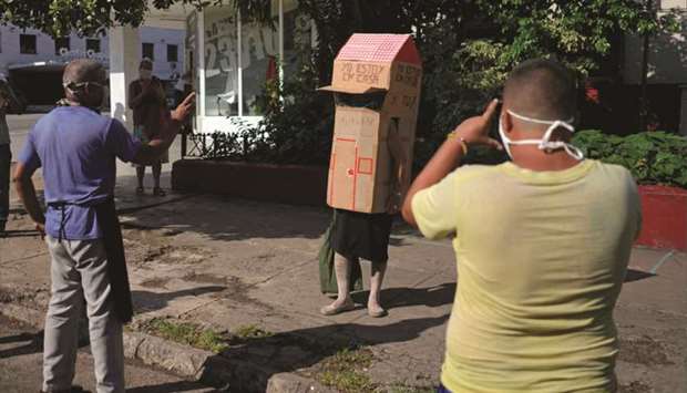 People take pictures of retired nurse Feridia Rojas, 82, as she wears cardboard box in Havana.