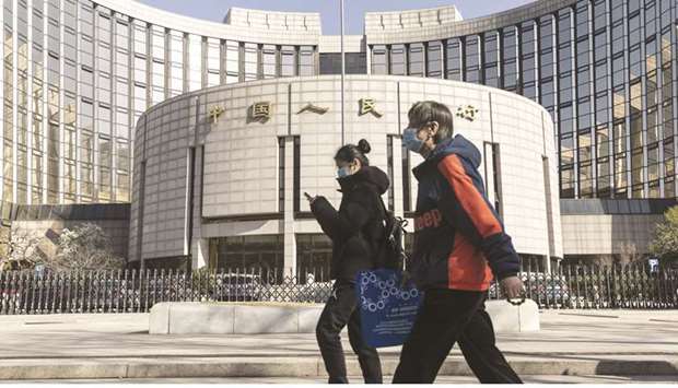 Pedestrians wearing protective masks walk past the Peopleu2019s Bank of China building in Beijing. The PBoC is trying to bring down borrowing costs across the economy to aid the recovery from the coronavirus slump in the first quarter, without engaging in large-scale debt stimulus seen elsewhere.